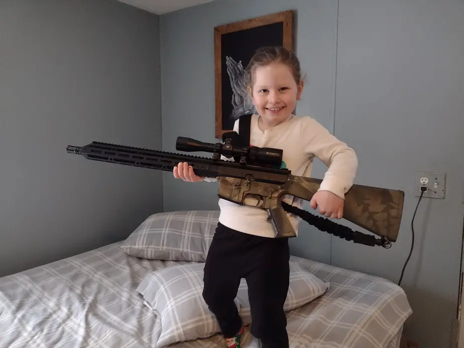 Young girl holding an AR-15 hunting rifle